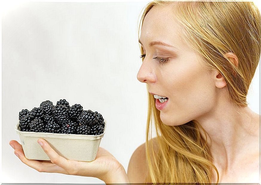 Woman holding bowl of blackberries.