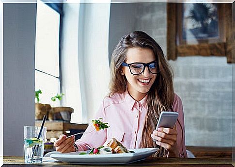 Woman eating with mobile phone