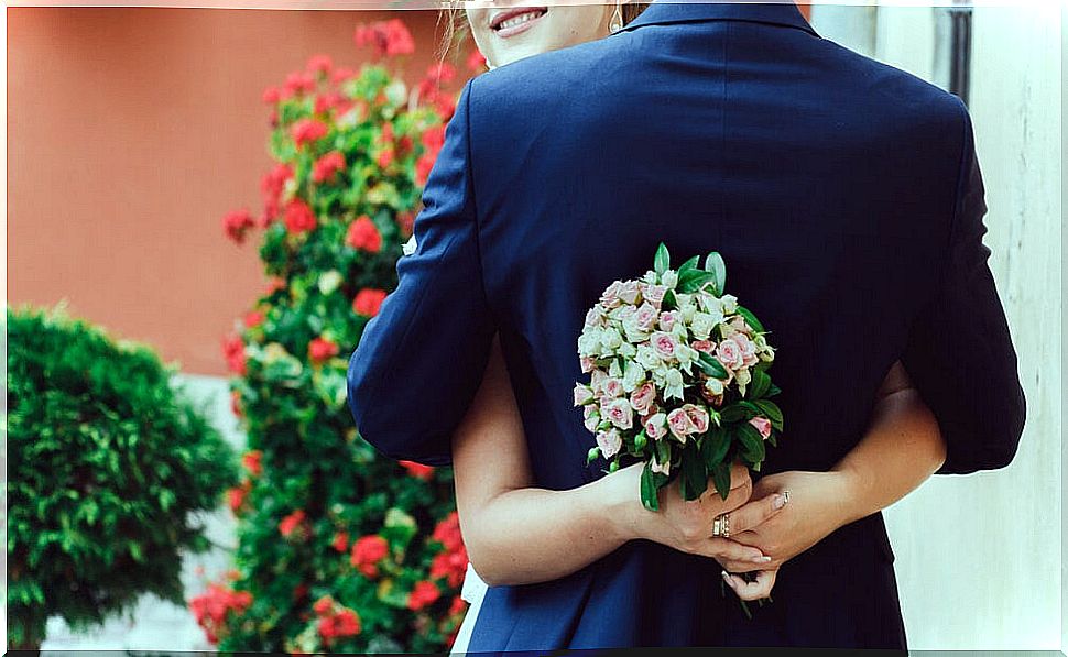 Just married wedding couple hugging with a bouquet of flowers in hand.