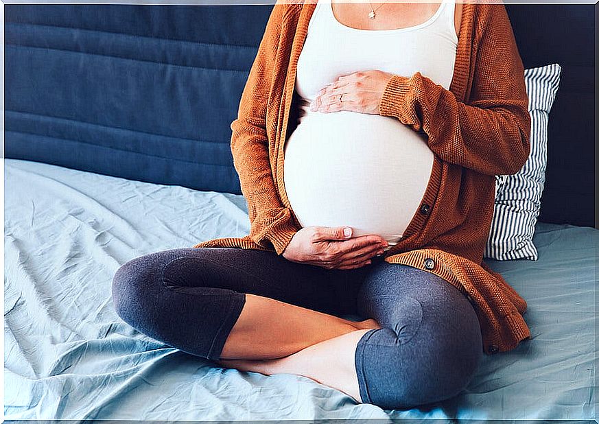 Pregnant woman sitting on the bed.